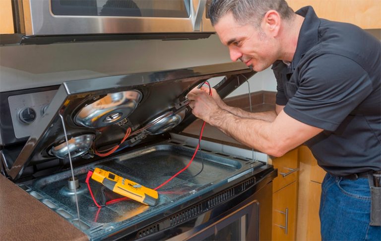 A man working on stove repair using a tool, focused on fixing the stove's internal components.