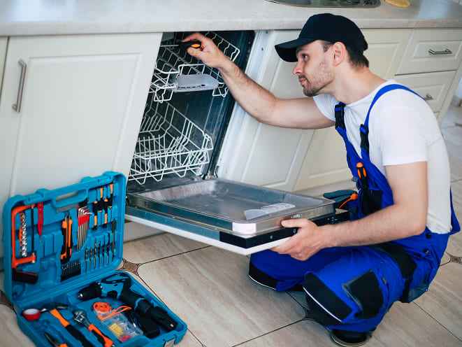 A professional appliance repair worker is trying to fix an oven apparently. 