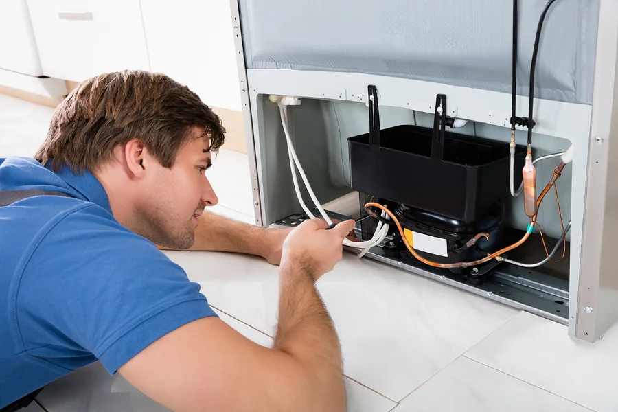 A man is focused on an outdoor Marvel refrigerator in a kitchen setting.